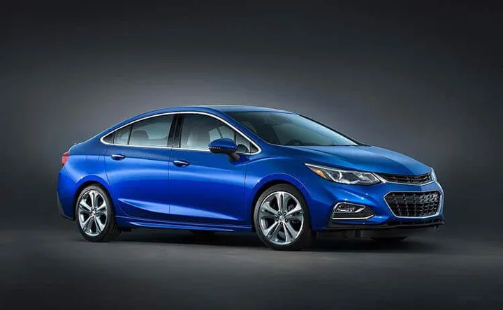Blue four-door sedan shown from the front side against a dark studio background